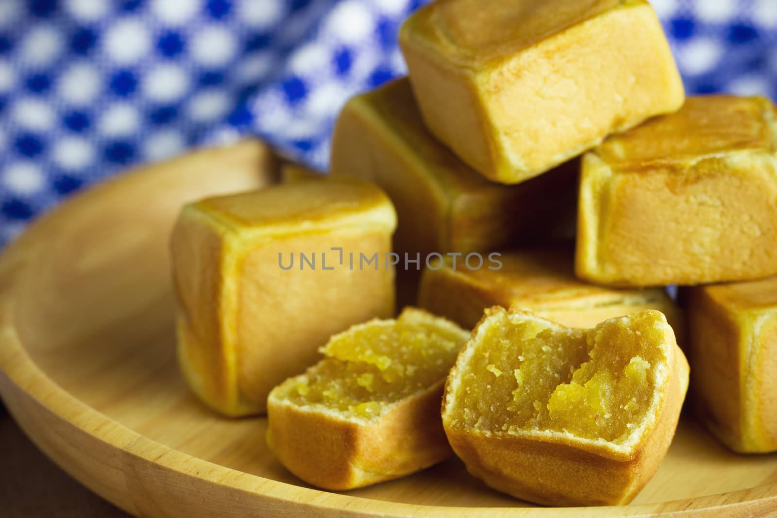 Closeup chinese cakes dice shaped are placed on a brown wooden table and have blue patterned tablecloths.