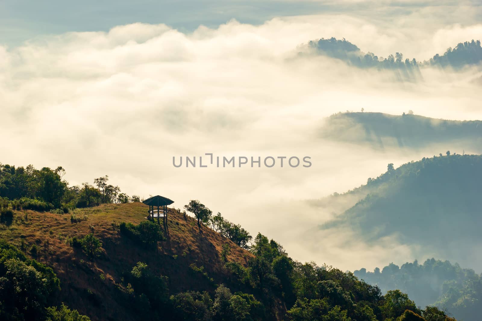 The pavilion is located in the middle of the mountain and there is a fog with the sun shining light which creates beautiful light and shadow.