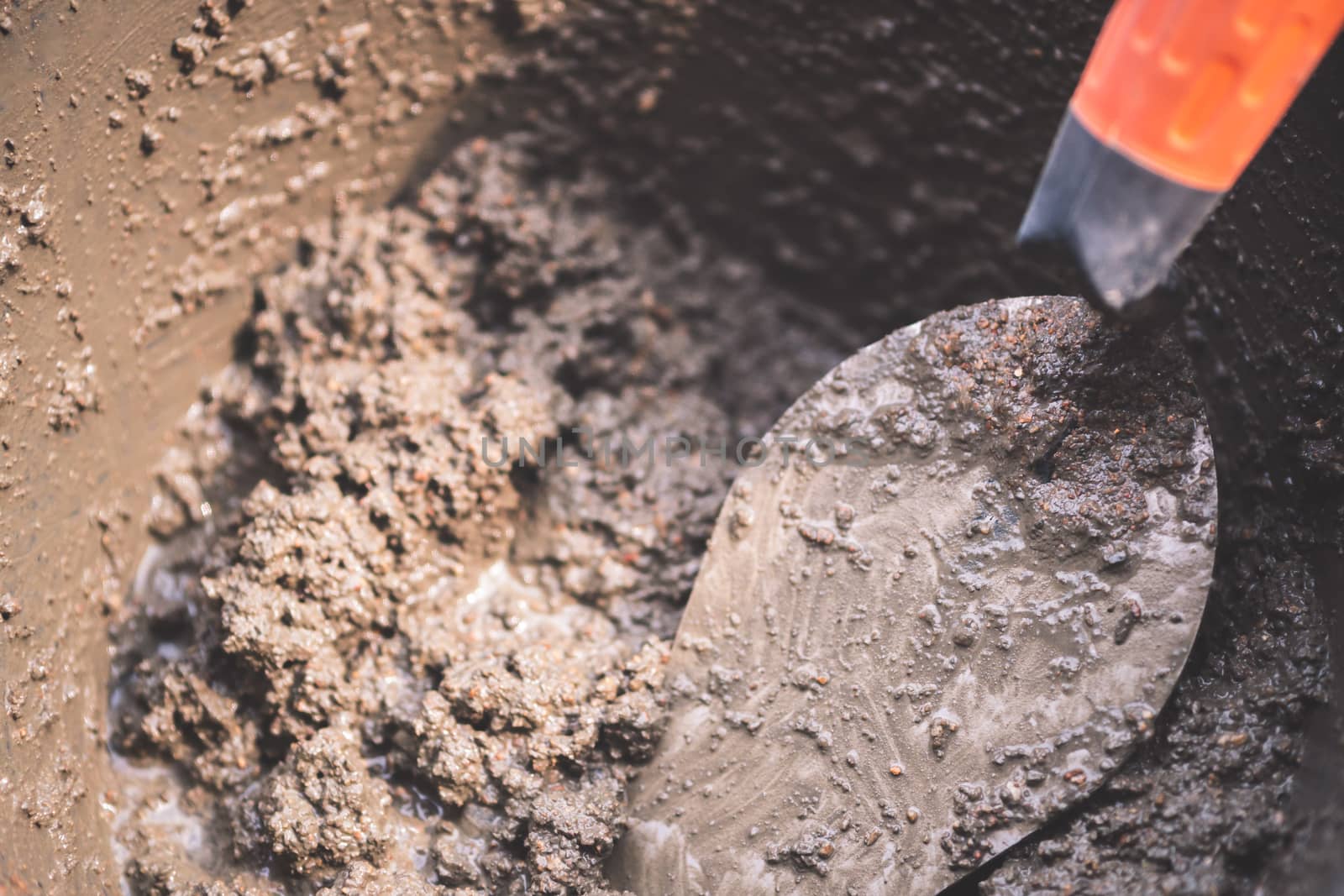 Closeup trowel in cement tub and sunlight. Mixing concrete to prepare for construction.