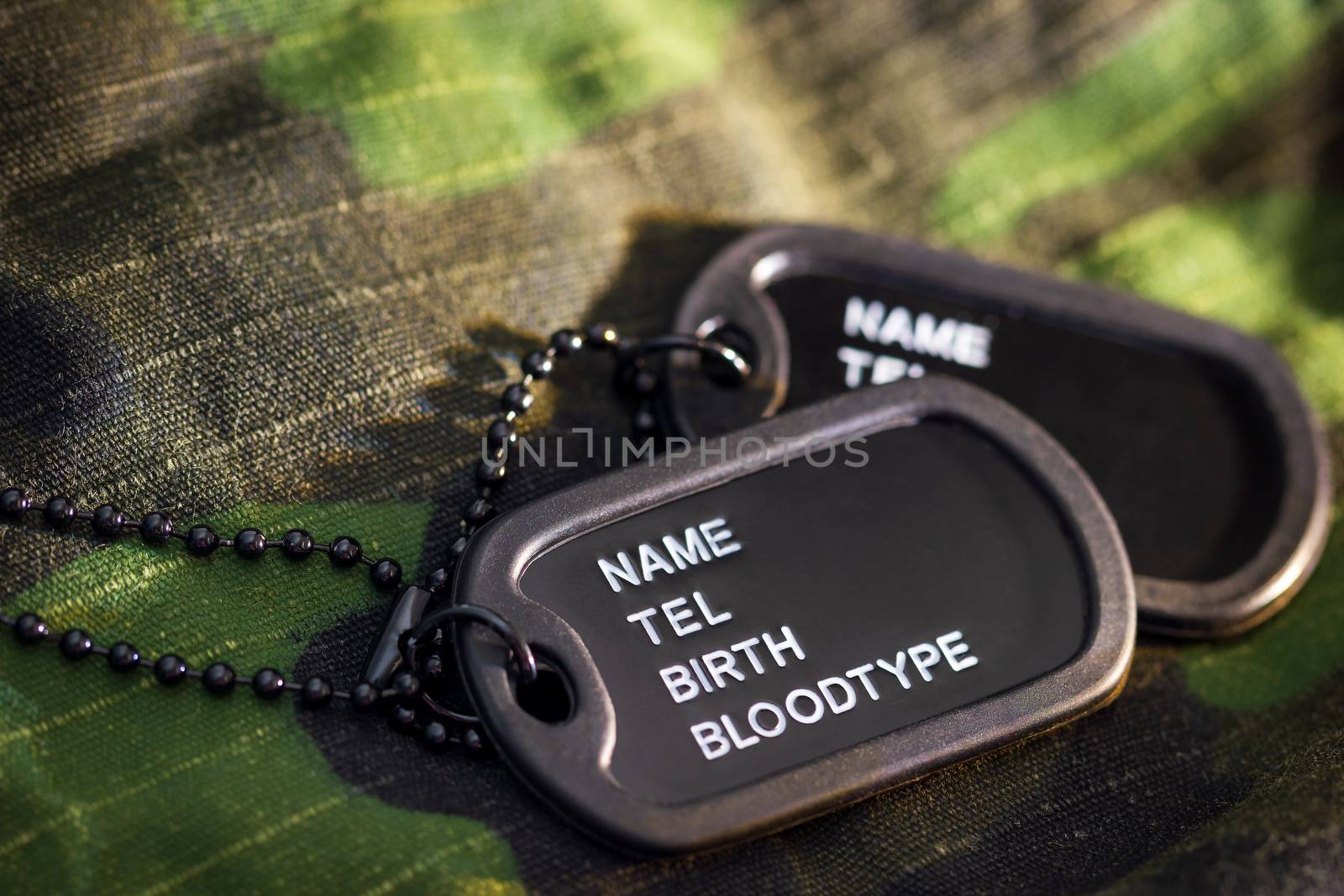 Soldier tag or dog tag laid on military jacket and morning sunlight. Concept of protecting for a new day.