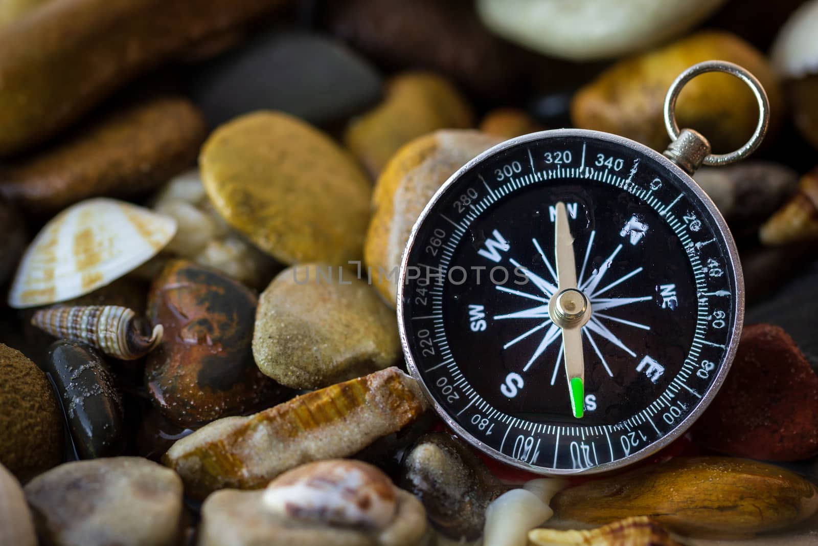 Compass on the pebbles and shell at riverside. Concepts of tourism and adventure.