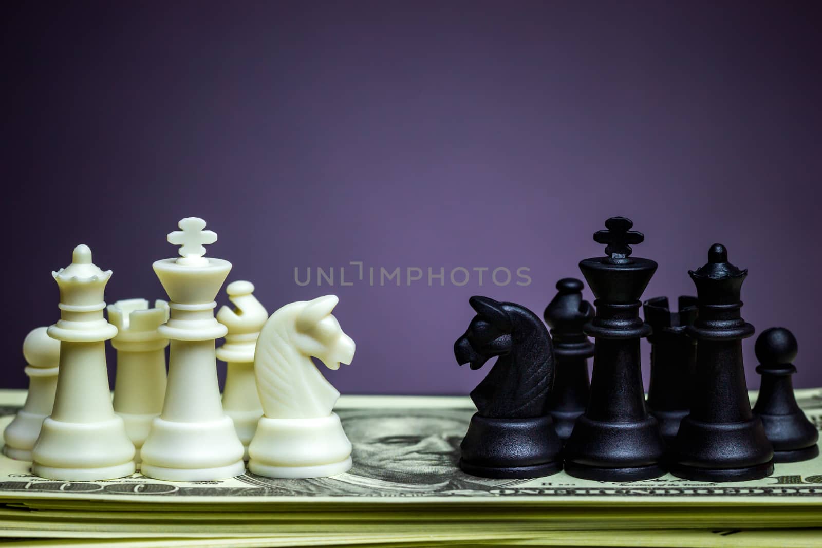 Both white and black chess face each other on a dollar banknote. Concept of business strategy or business war.