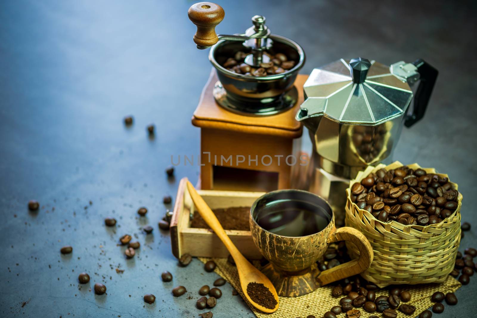 Brew black coffee in coconut cup and morning lighting. Roasted coffee beans in a bamboo basket and wooden spoon. Vintage coffee grinder and moka pot. Concept of coffee time in morning or start the new day.