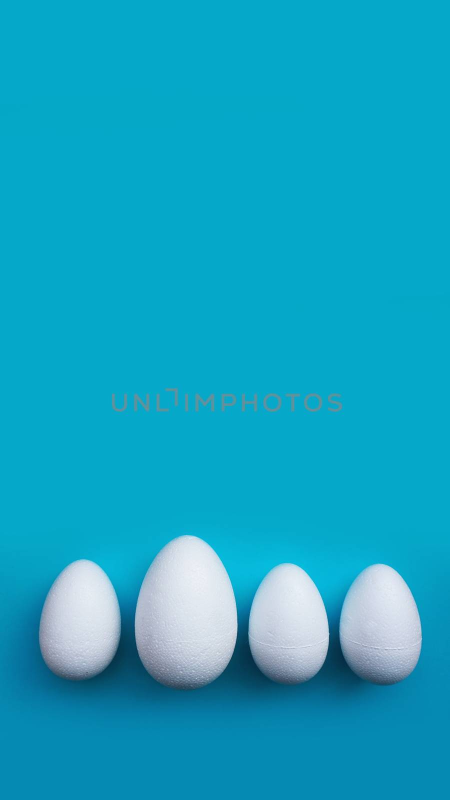 White foam eggs on blue background. Flat lay, top view. Easter concept.