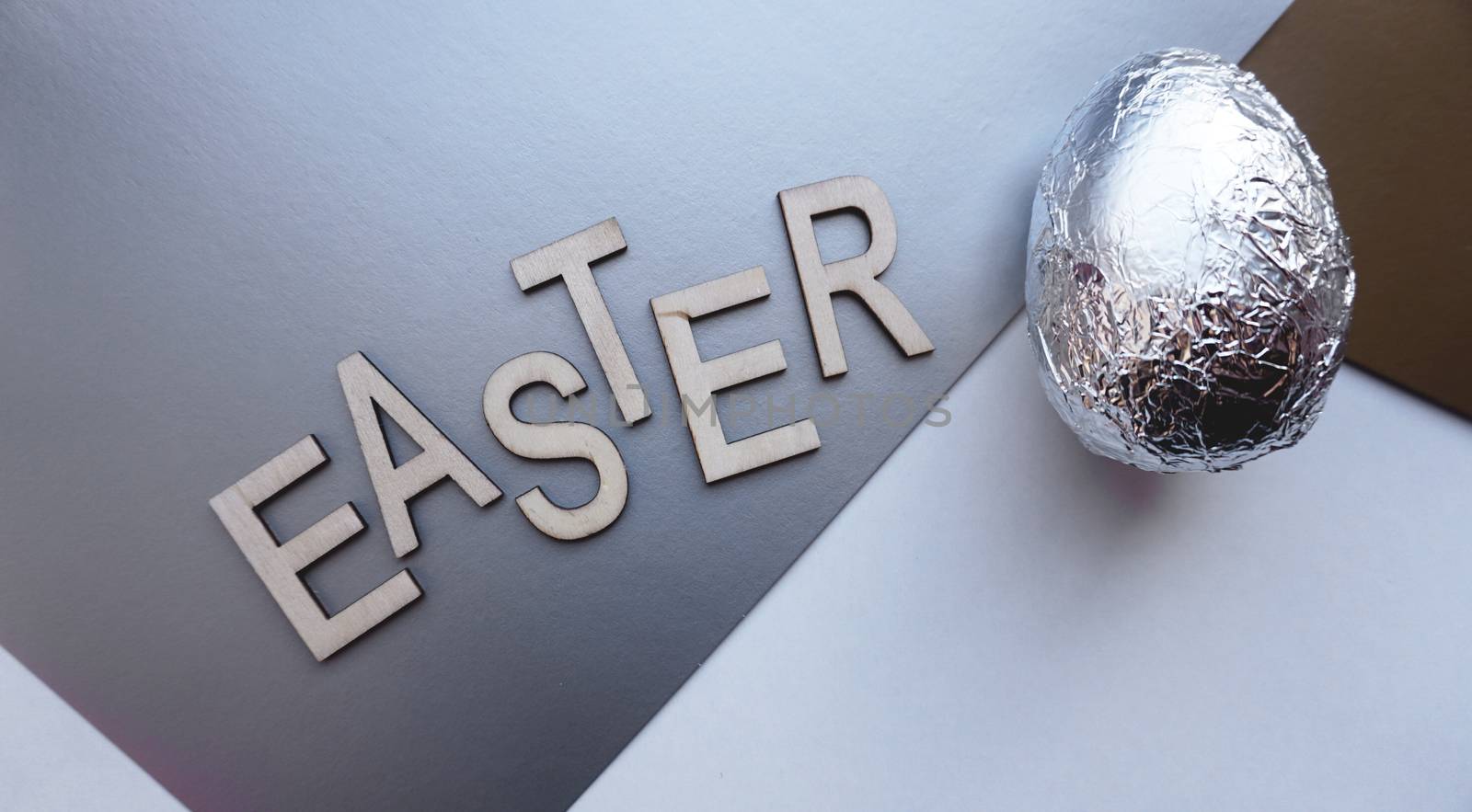 Egg in foil on silver background. Easter concept. With text Easter by natali_brill