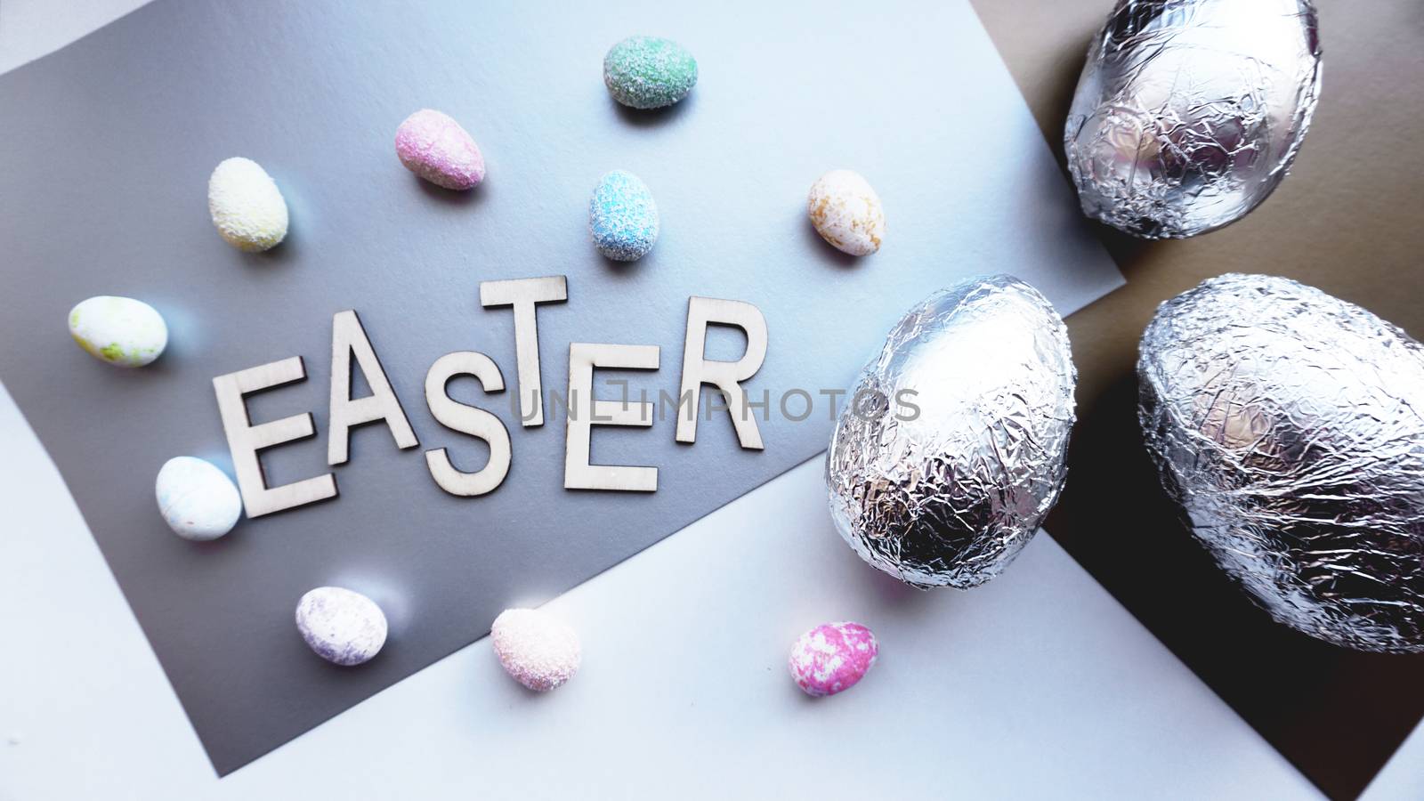 Eggs in foil on silver background. Easter concept. With text Easter by natali_brill