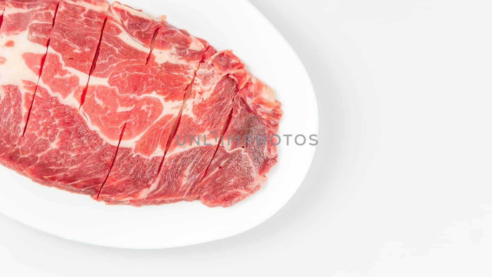 Top view of some raw beef on a plate over white background