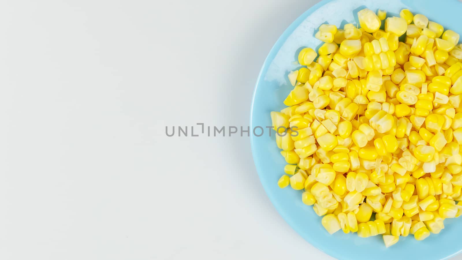 top view raw sweet corn on blue plate with copy space