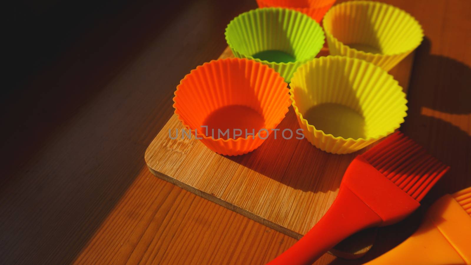 Silicone brush and cupcake liners on wooden table by natali_brill