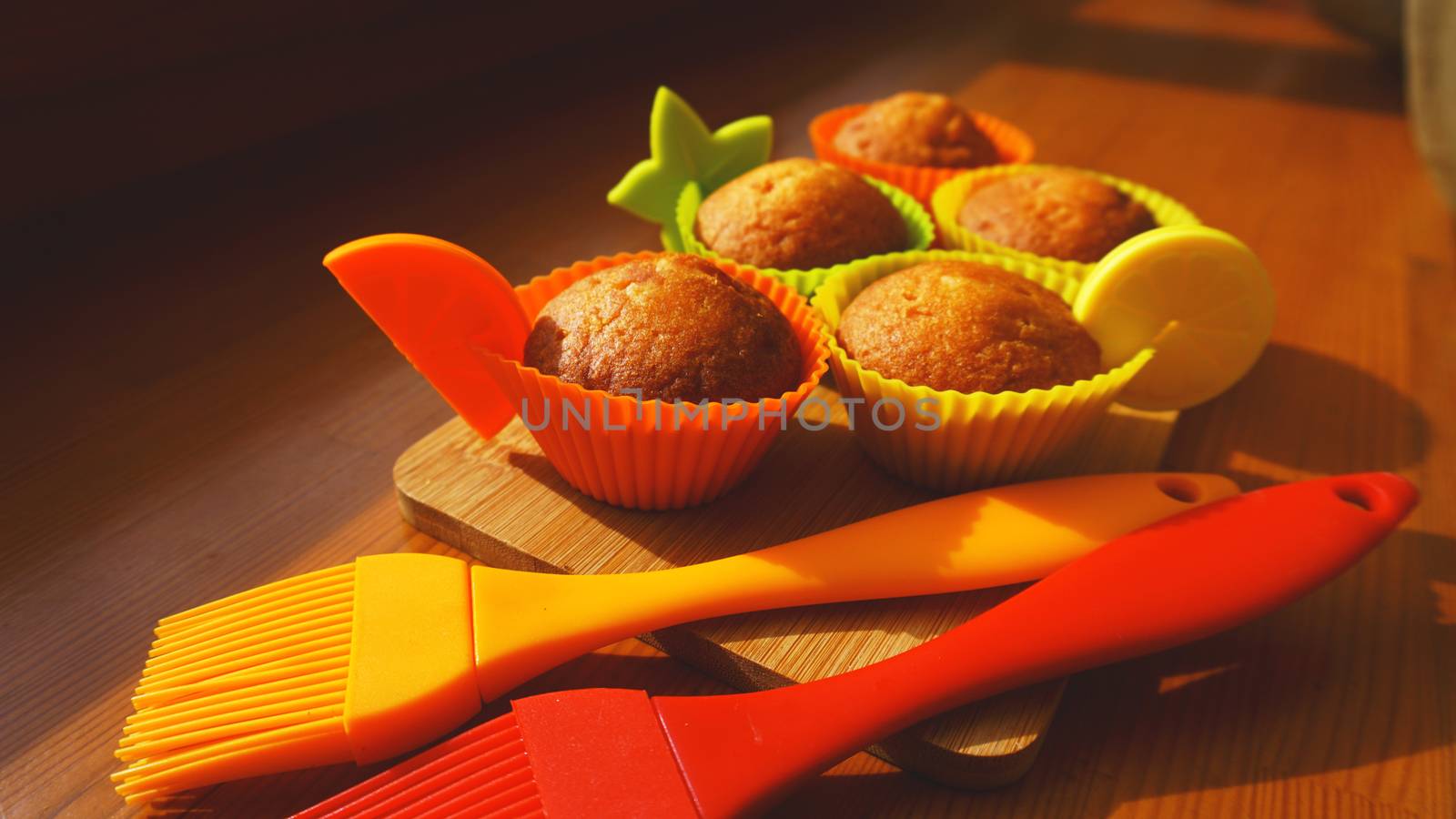 Simple mini muffins in colorful silicone bakeware. Silicone cup baking cupcakes and silicone brushes. Kitchen and cooking concept on wooden background