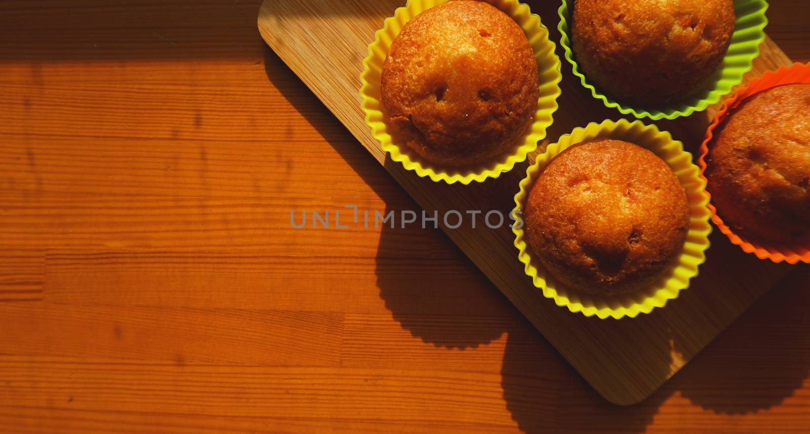 Simple mini muffins in colorful silicone bakeware. Free space. Closeup. Kitchen and cooking concept on wooden background