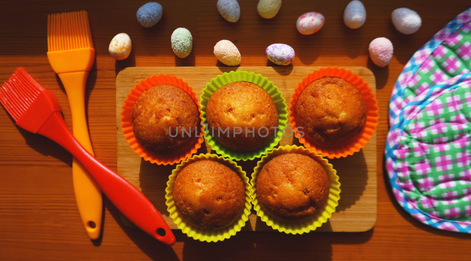 Mini Cakes Decorated with Eggs, Easter Dessert. Simple mini muffins in colorful silicone bakeware. Kitchen and cooking concept on wooden background