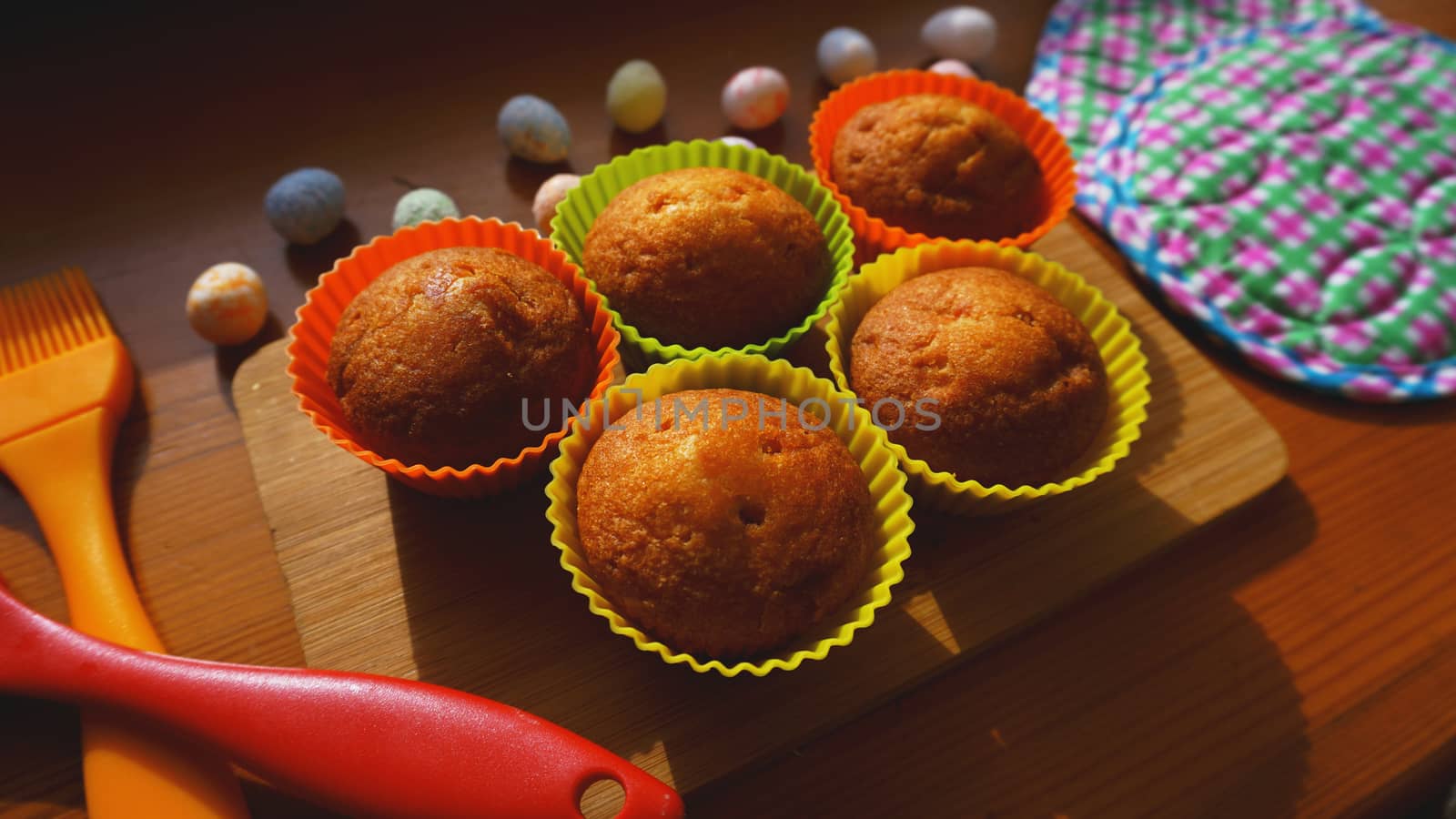 Mini Cakes Decorated with Eggs, Easter Dessert. Simple mini muffins in colorful silicone bakeware. Kitchen and cooking concept on wooden background