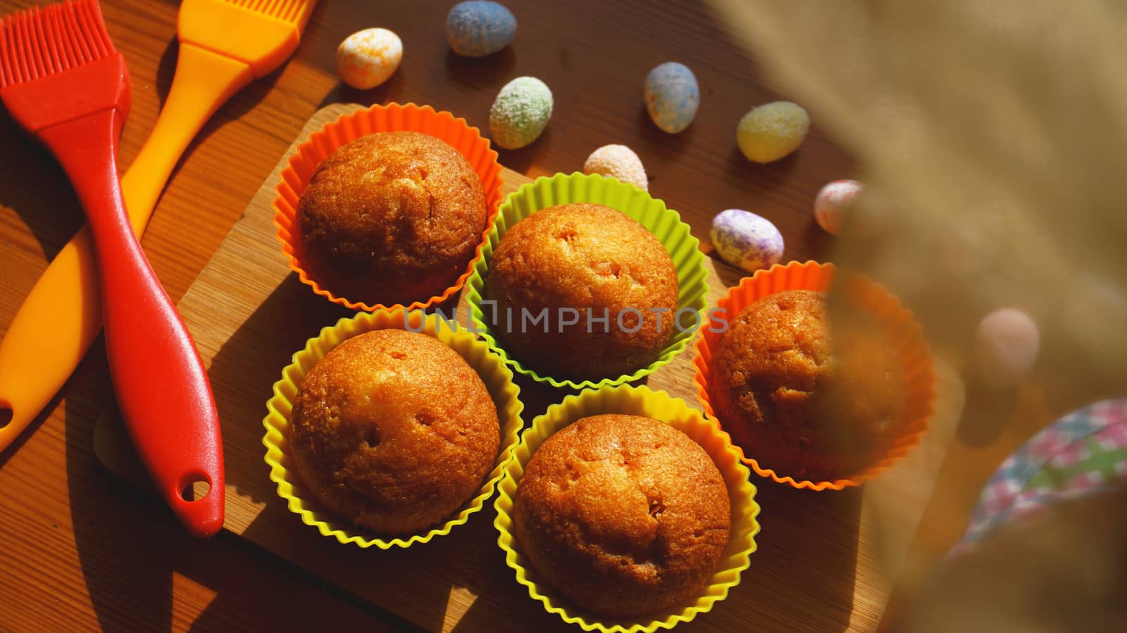 Mini Cakes Decorated with Eggs, Easter Dessert. Simple mini muffins in colorful silicone bakeware. Kitchen and cooking concept on wooden background