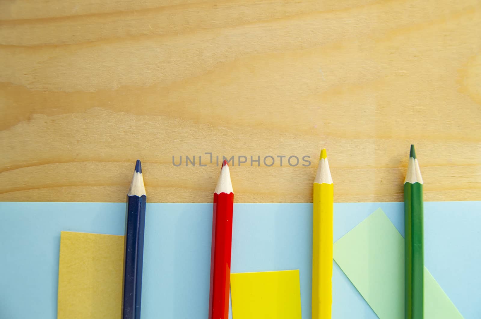 Flat lay, colored pencils, blue and wooden background, back to school, copy space.