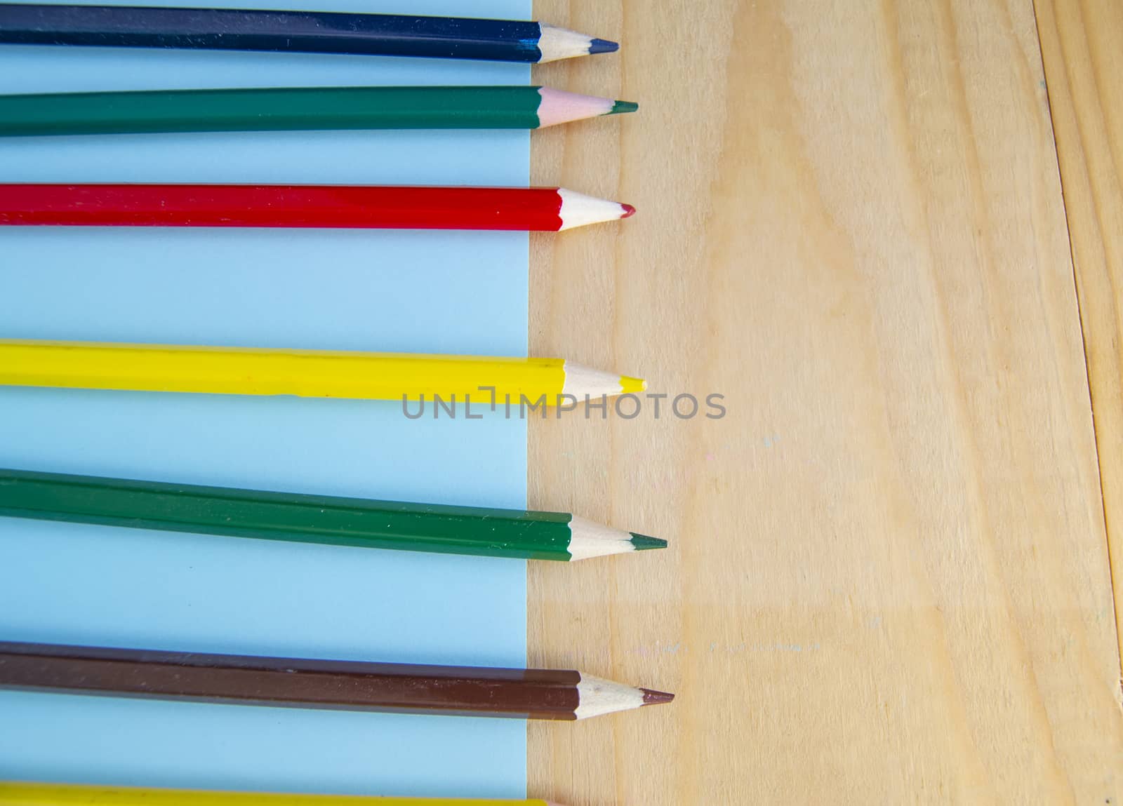 Flat lay, colored pencils, blue and wooden background, back to school, copy space.