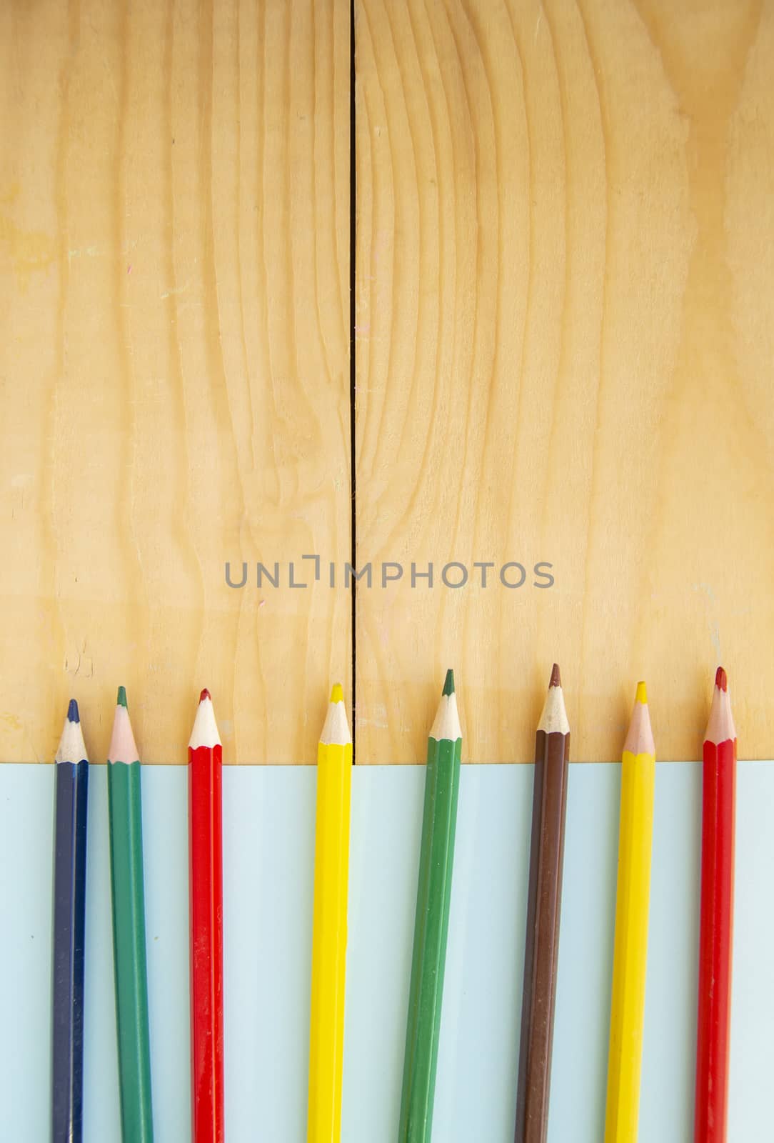 Flat lay, colored pencils, blue and wooden background, back to school, copy space.