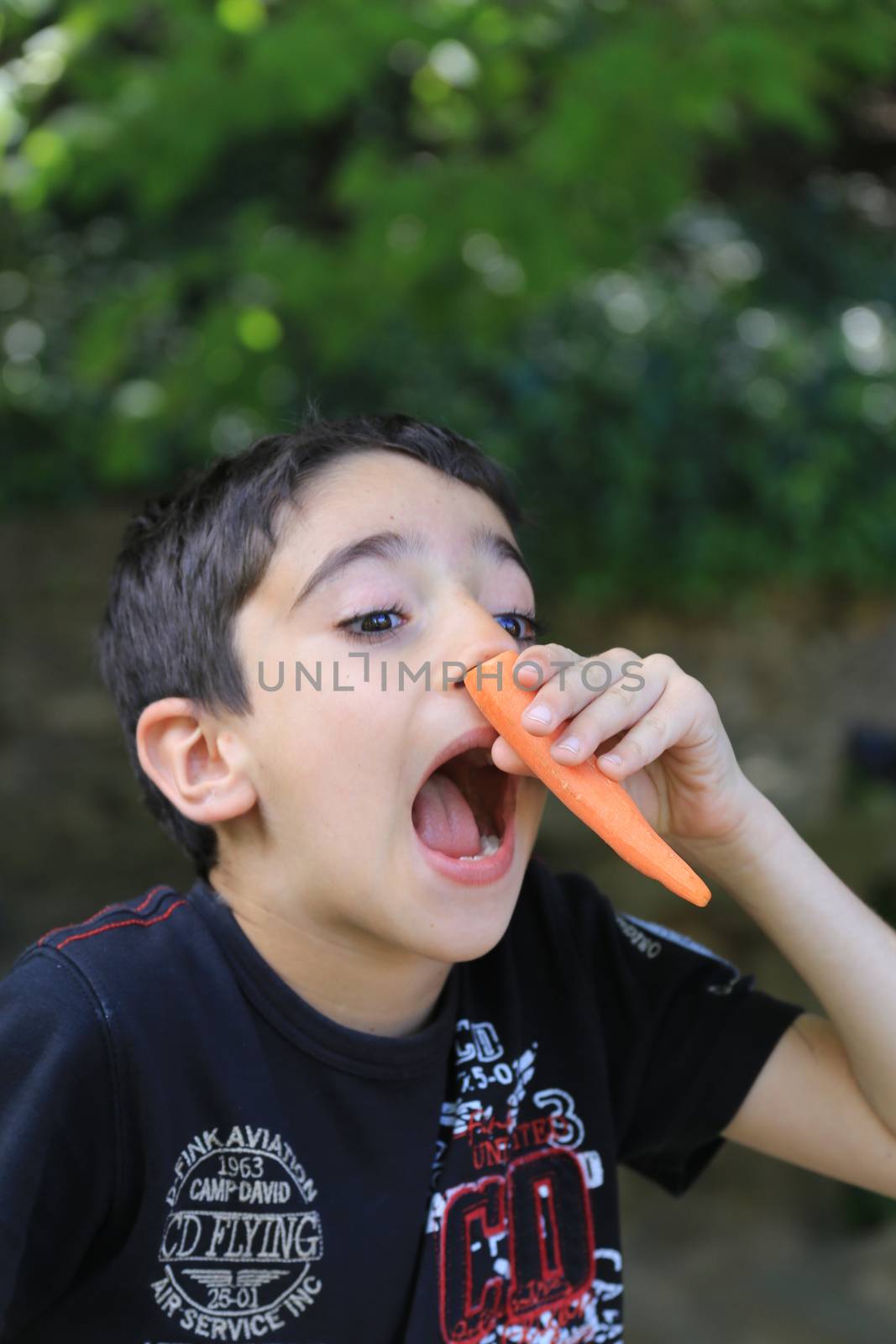 Playful boy making nose with peeled carrot by Anelik