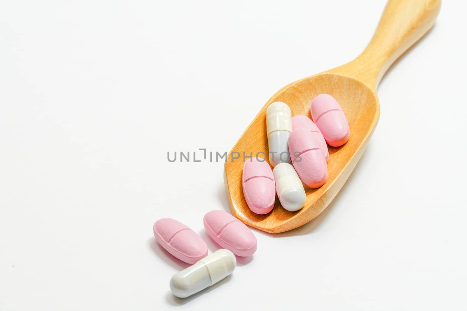 Medicine on a wooden spoon and on a white background