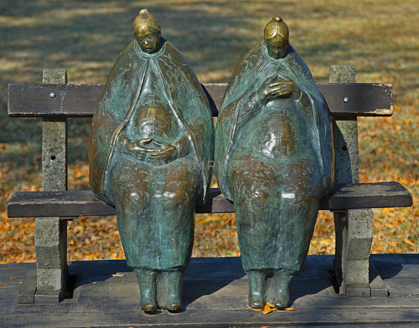 Two women marble figurines sitting on a bench