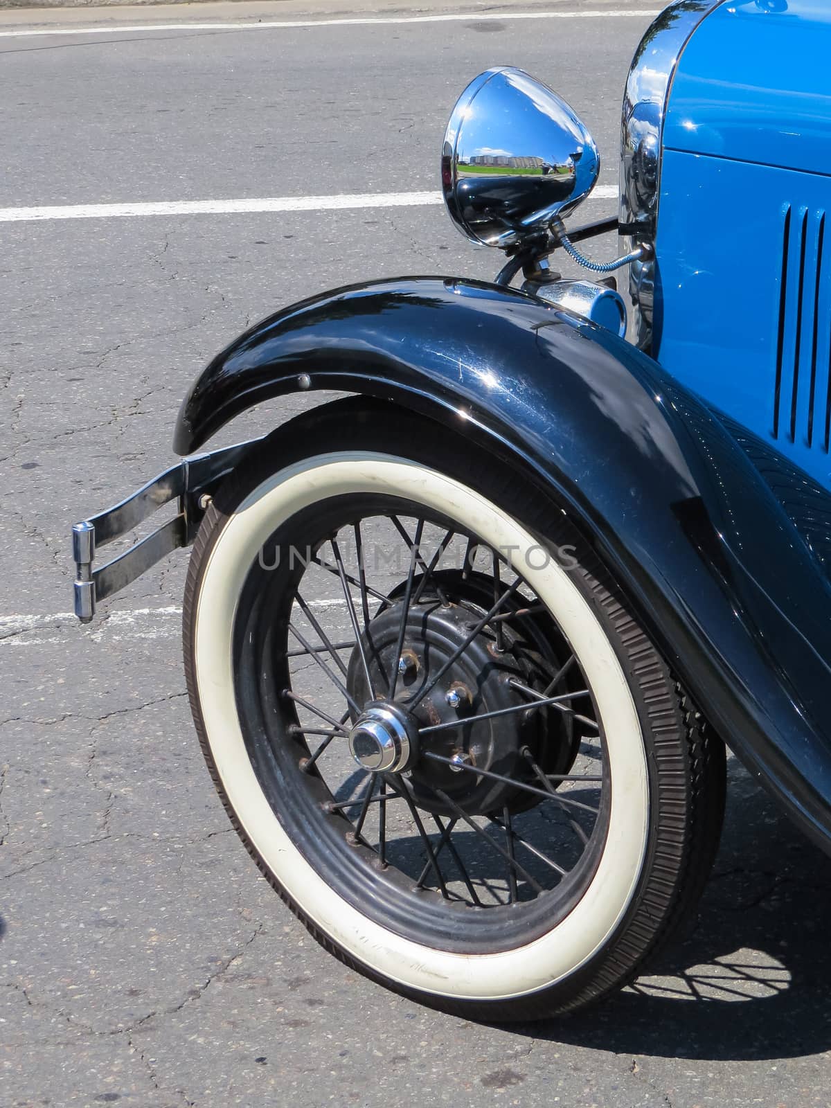 Old blue classic car, wheel detail and mudguards and chrome in sunny day.