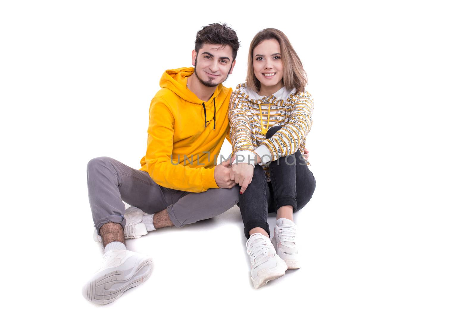 Smiling couple in yellow sitting on white in studio