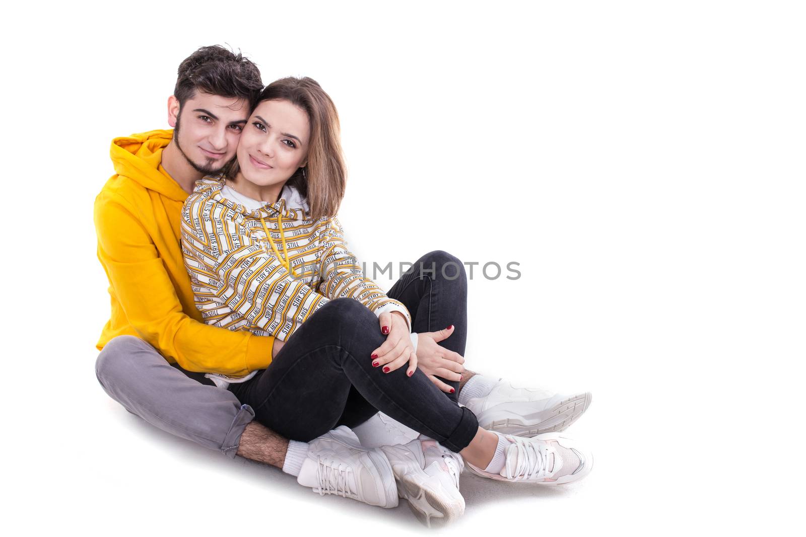 Young couple in yellow hugging and sittin in white studio