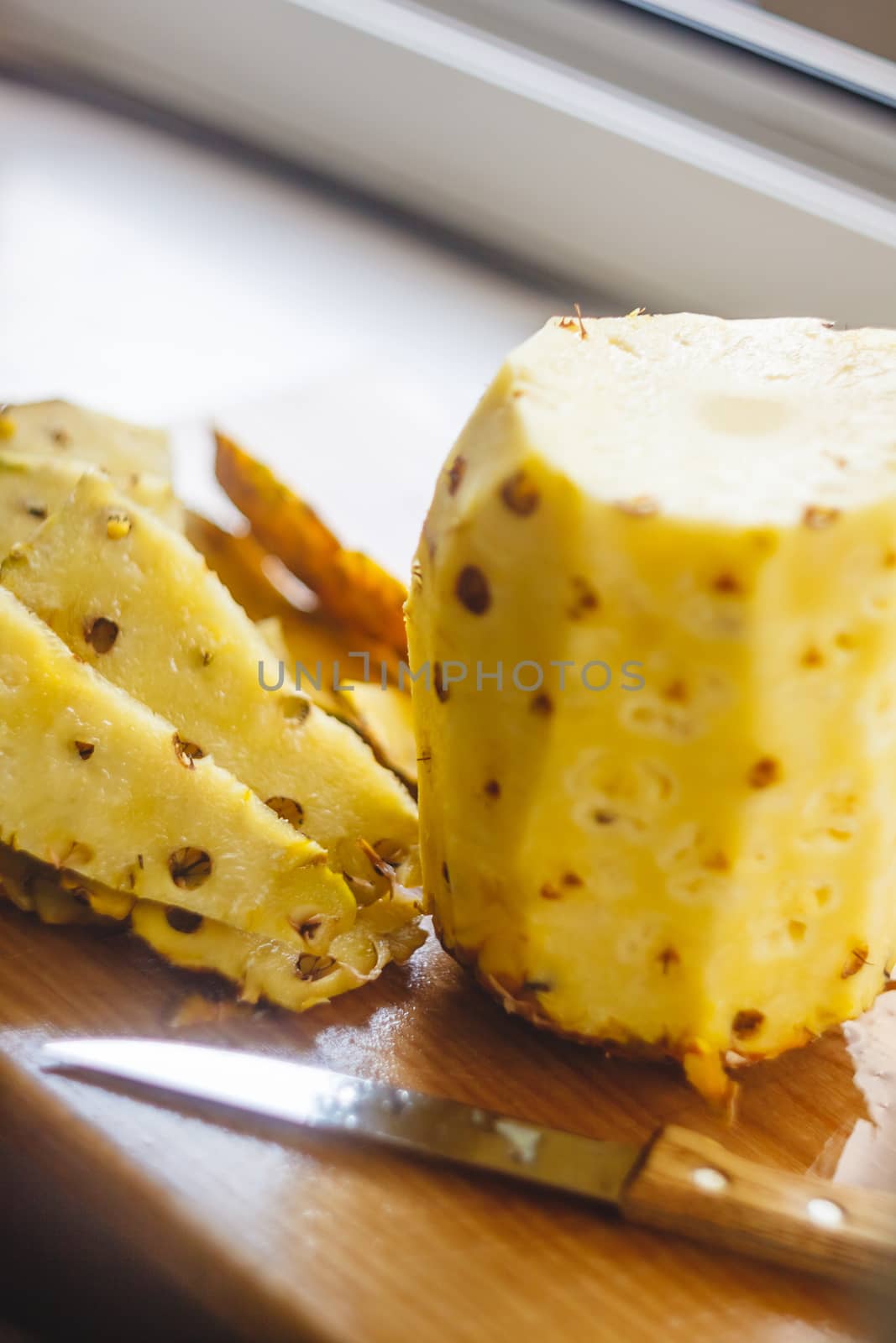 Pineapple cleaning, chunks, knife lie on the board.