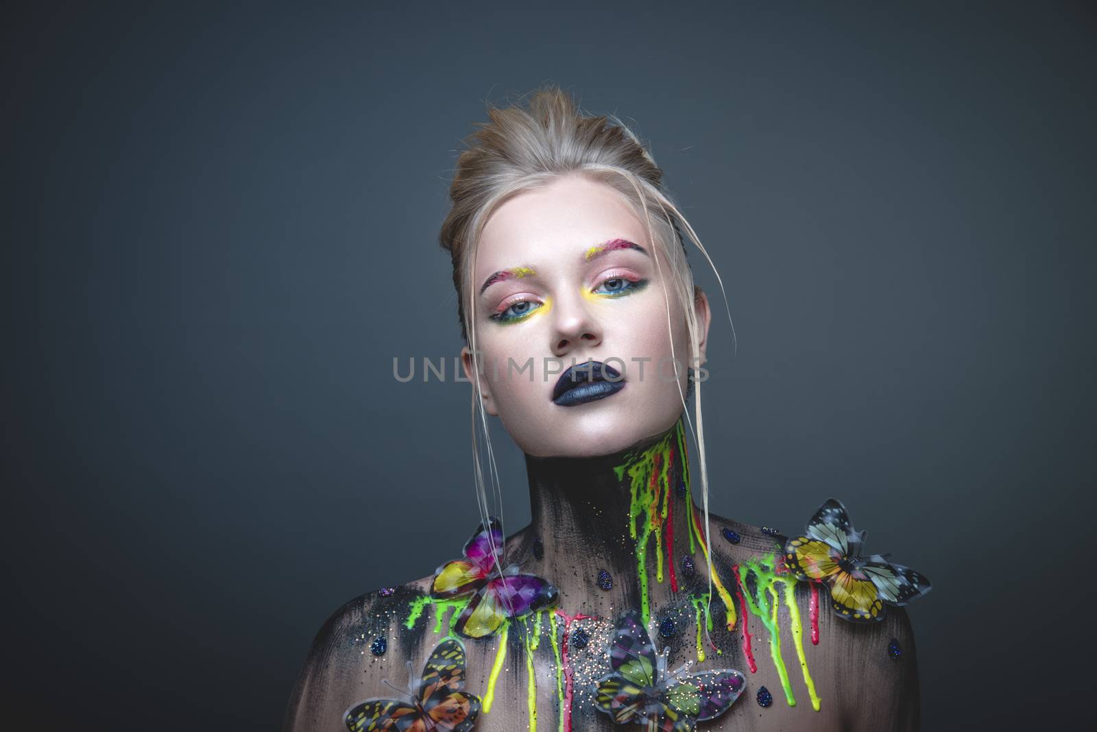 Emotional portrait of a young girl with creative makeup and colorful butterflies on her shoulders