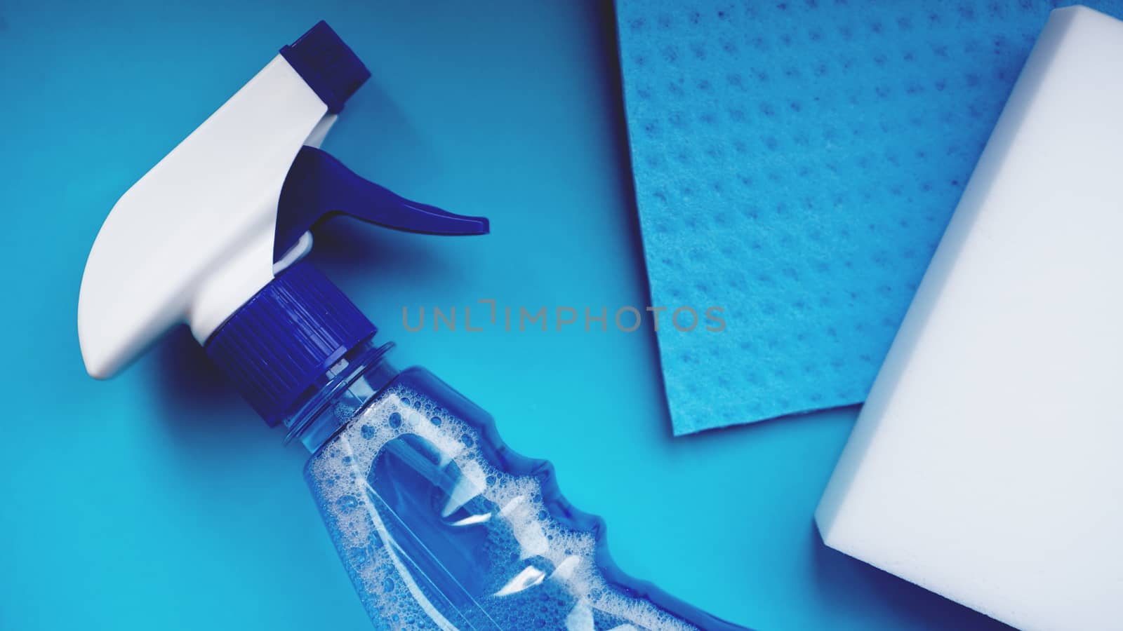 Housework, housekeeping and household concept - cleaning rag, detergent spray on blue background