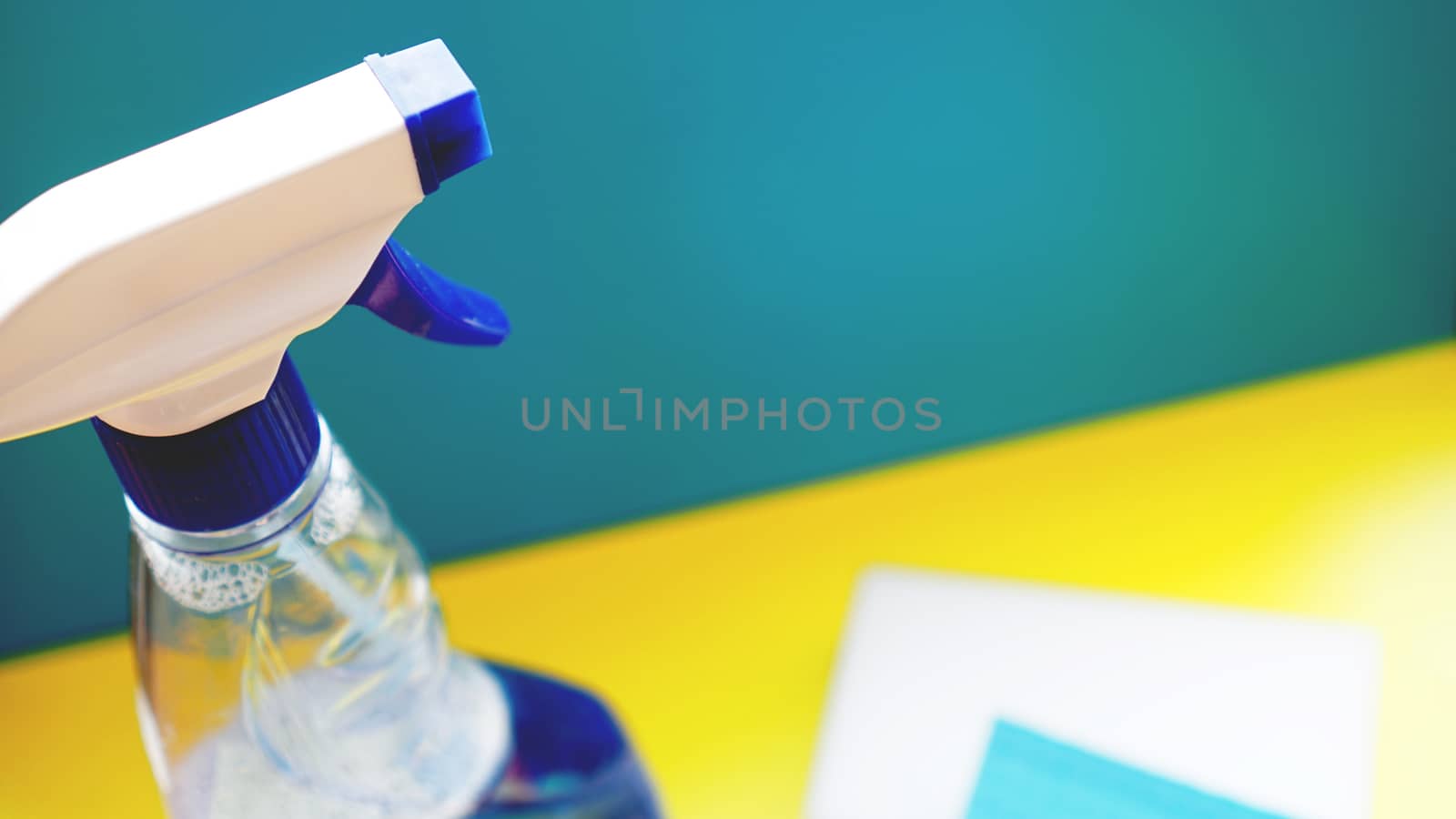 Housework, housekeeping and household concept - cleaning rag, detergent spray on blue background