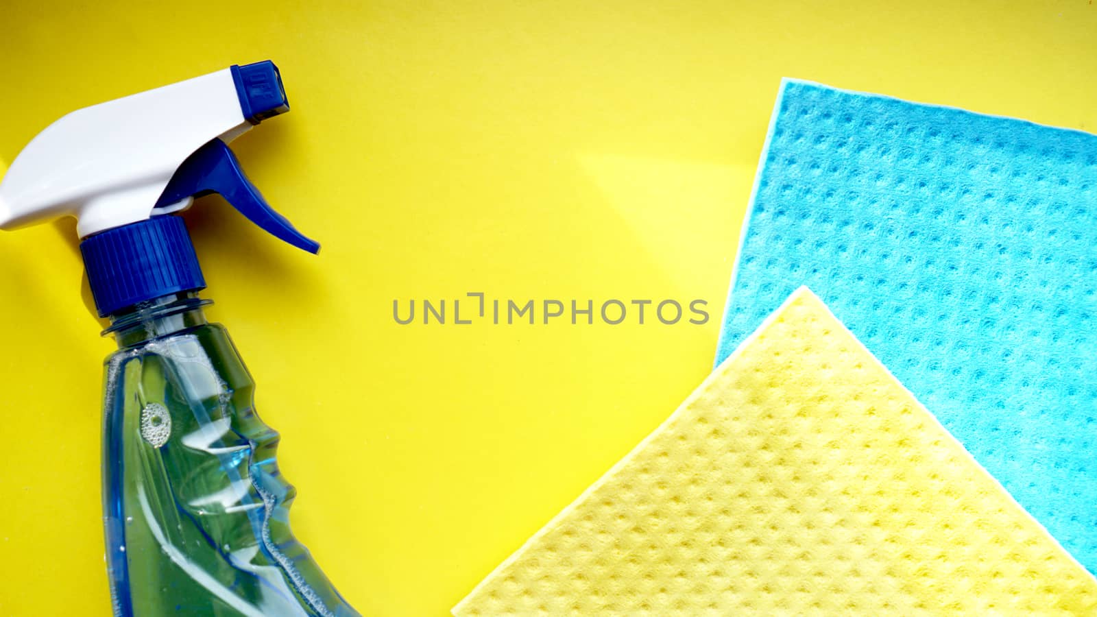 Housework, housekeeping and household concept - cleaning rag, detergent spray on yellow background
