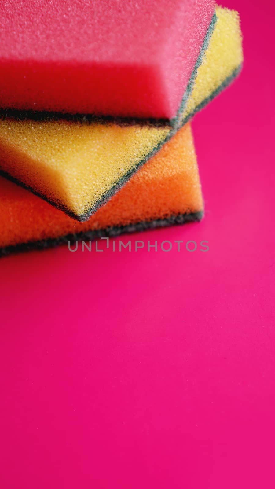 Sponges - close-up. Household cleaning concept. Colorful orange pink yellow sponges on pink background, soft focus, copy text.