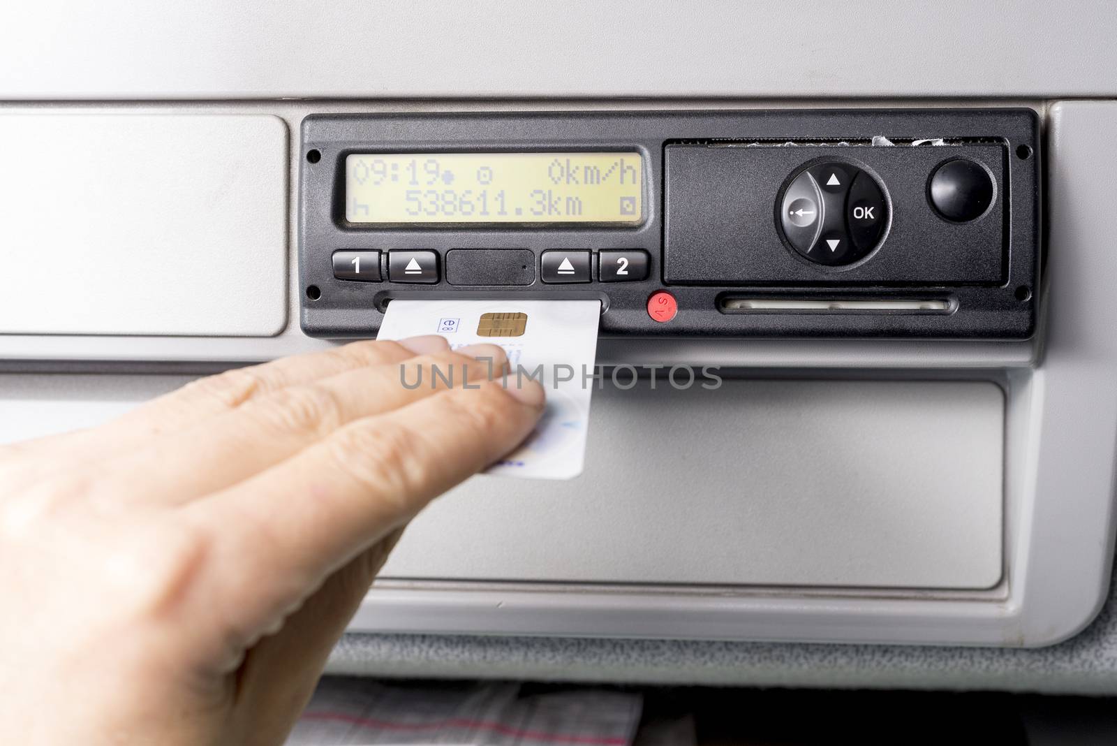 Digital tachograph and drivers hand inserting drivers card in it. No personal data.