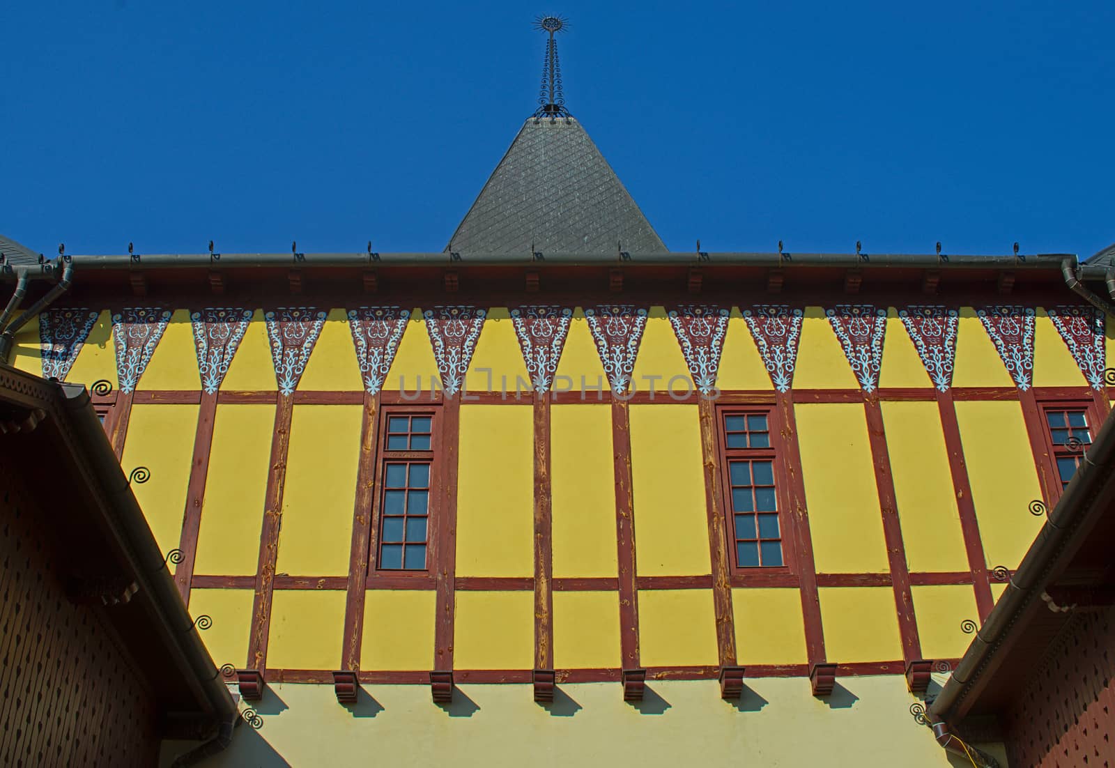 View on old style yellow wall with two windows and square tower on a building by sheriffkule