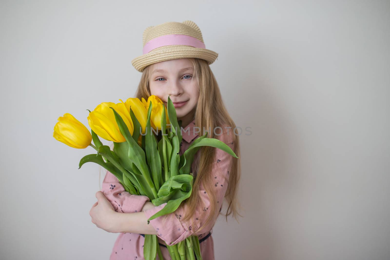 Pretty teen girl in pink dress with big bouquet of yellow tulips