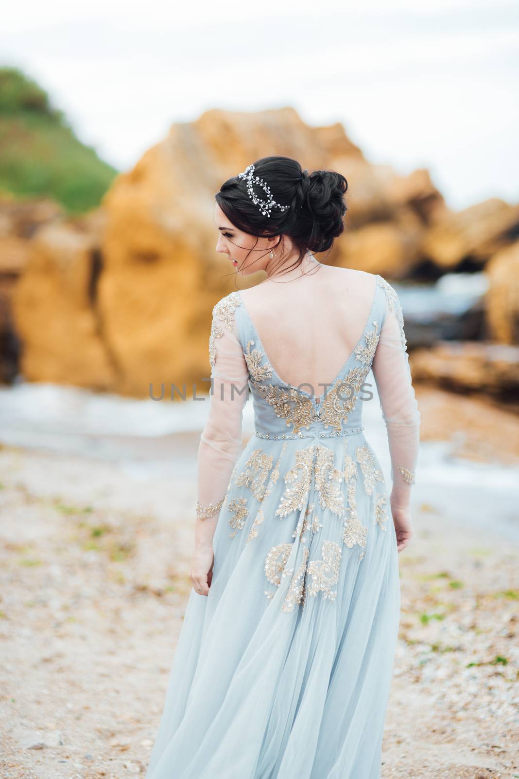 bride in a blue light dress walking along the ocean