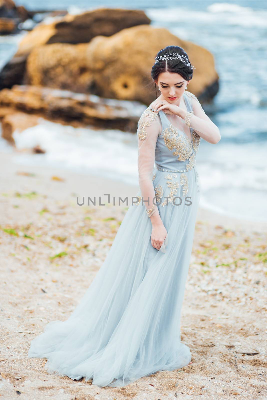 bride in a blue light dress walking along the ocean