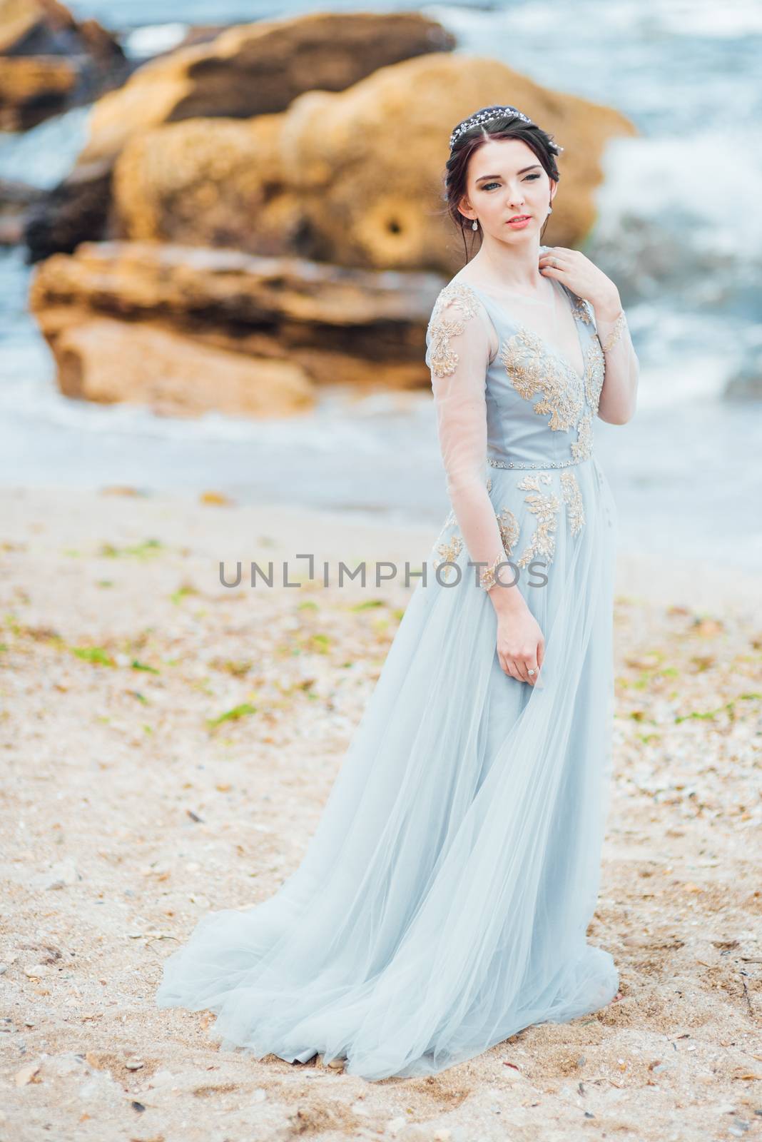 bride in a blue light dress walking along the ocean by Andreua