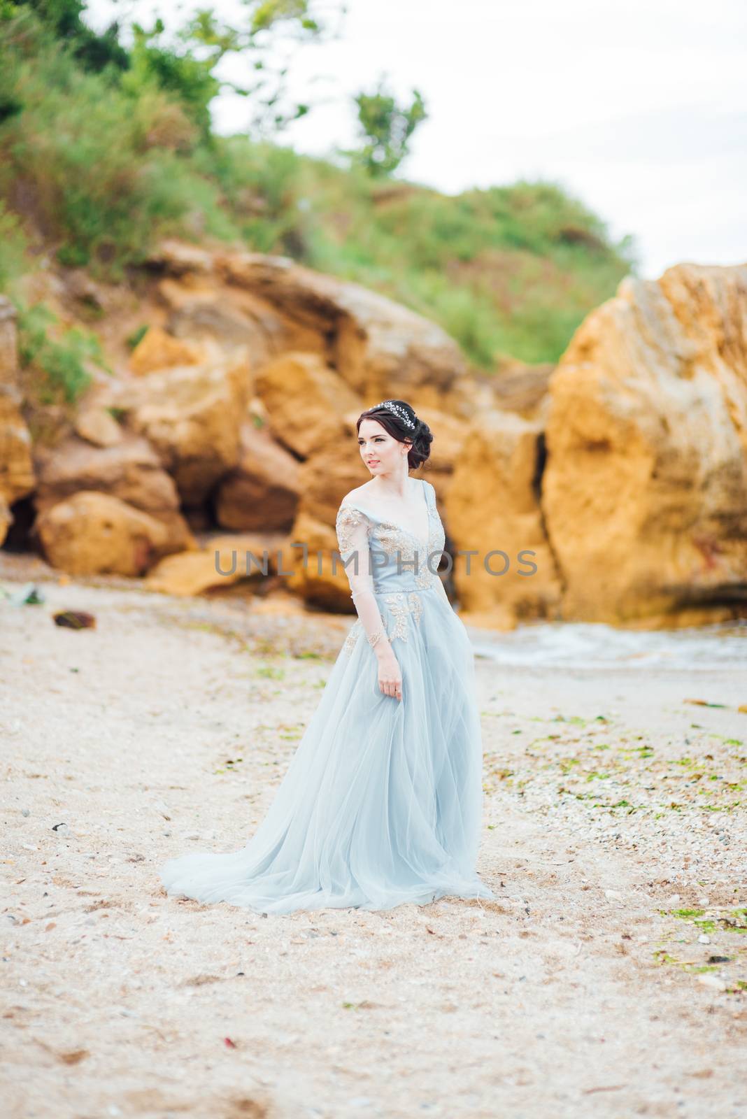 bride in a blue light dress walking along the ocean