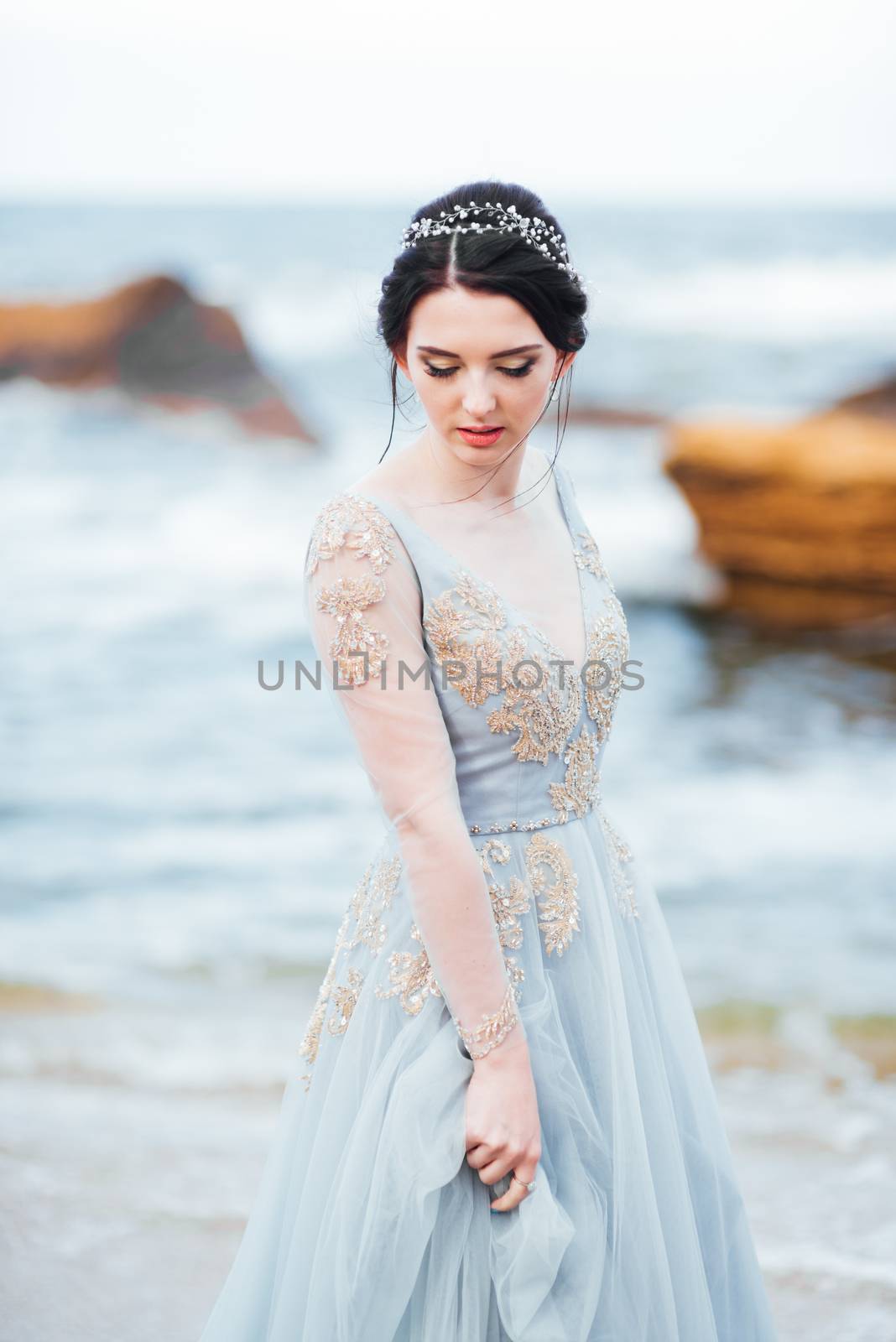 bride in a blue light dress walking along the ocean