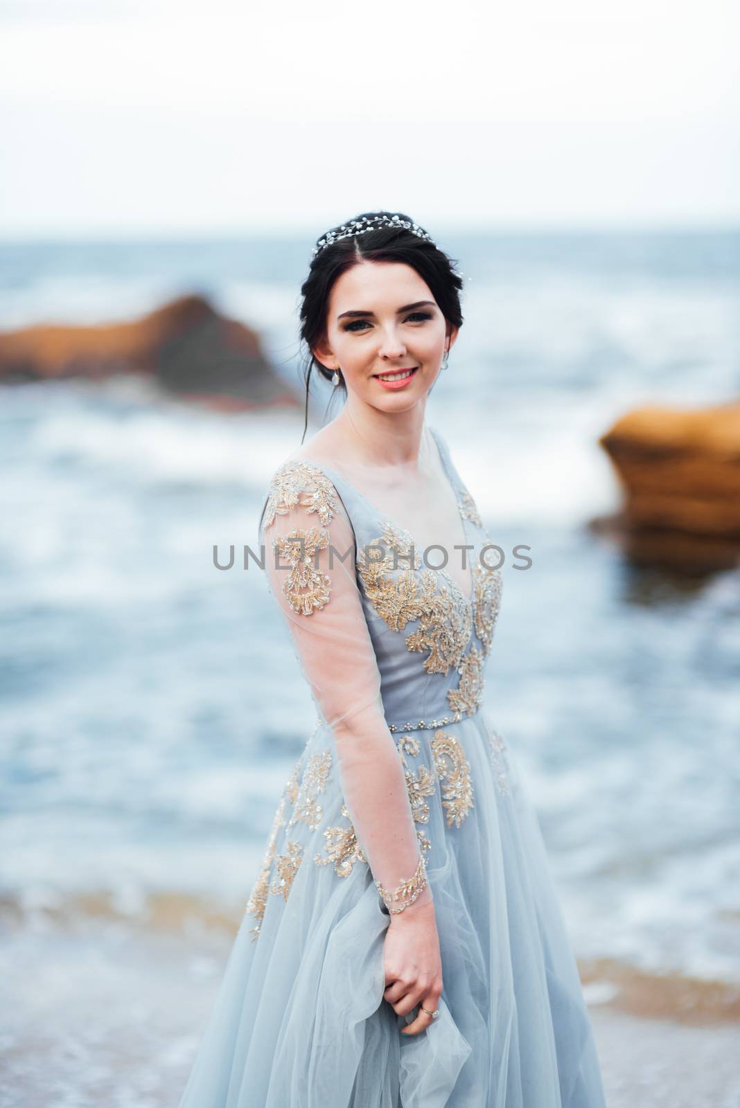 bride in a blue light dress walking along the ocean