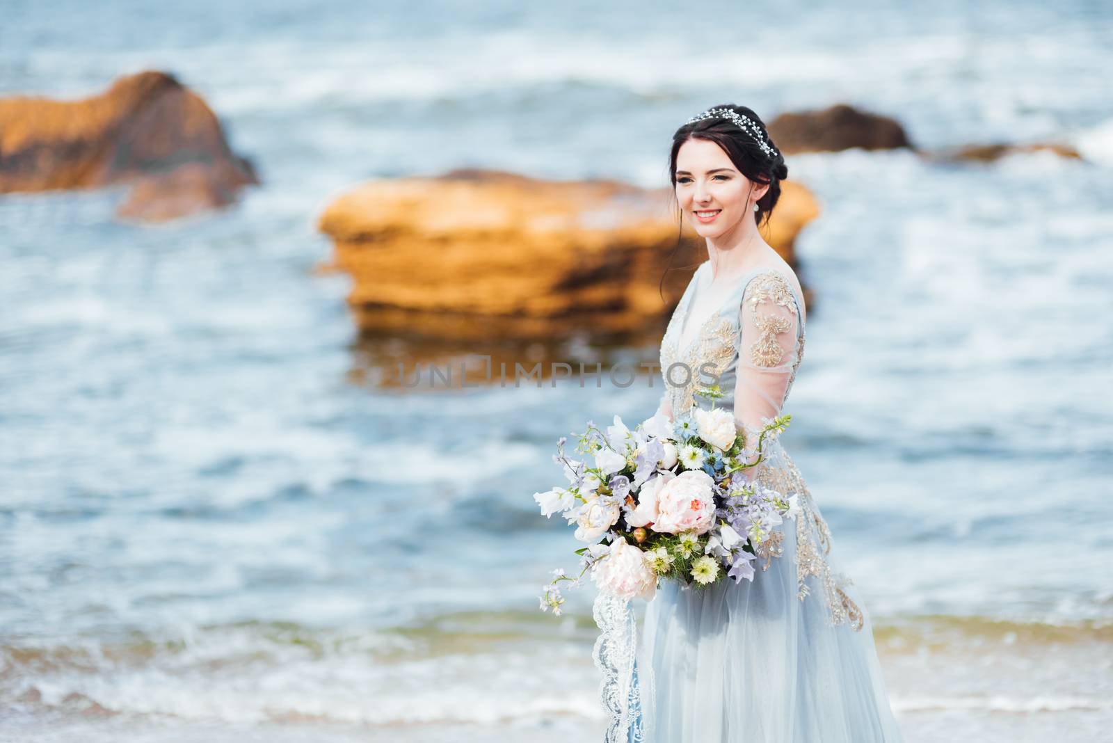 bride with a bouquet of flowers on the beach near the water