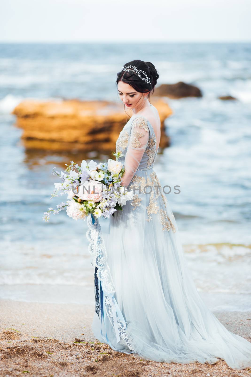 bride with a bouquet of flowers on the beach by Andreua