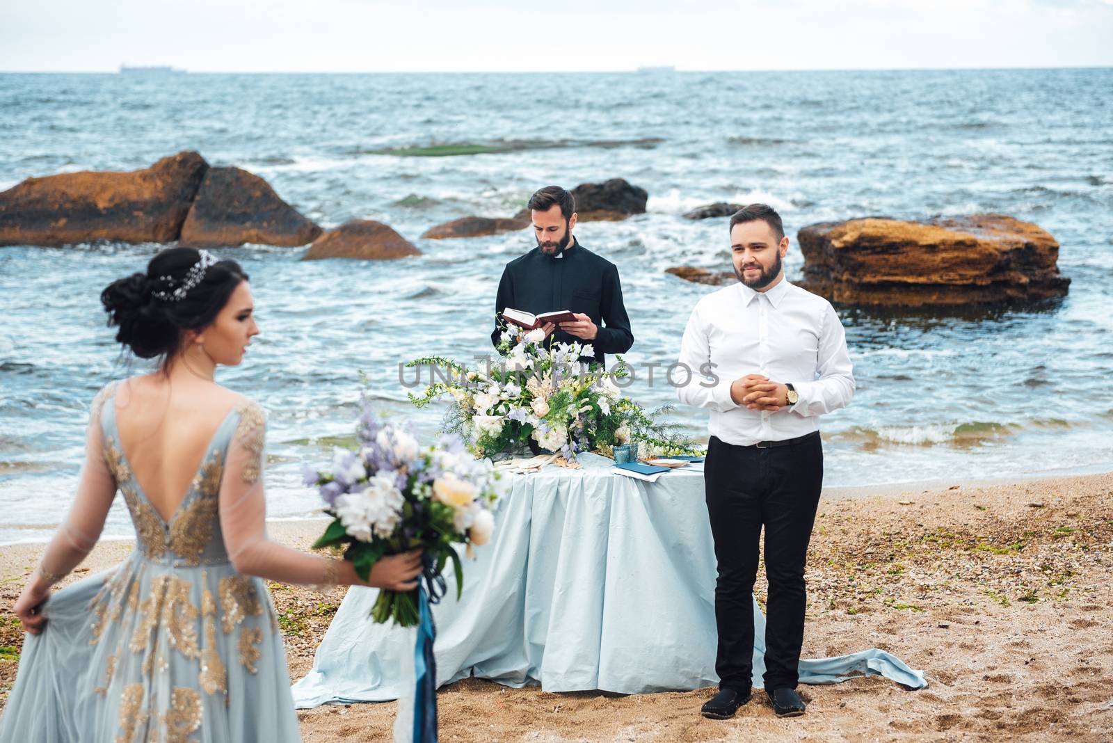 wedding couple on the ocean with a priest by Andreua