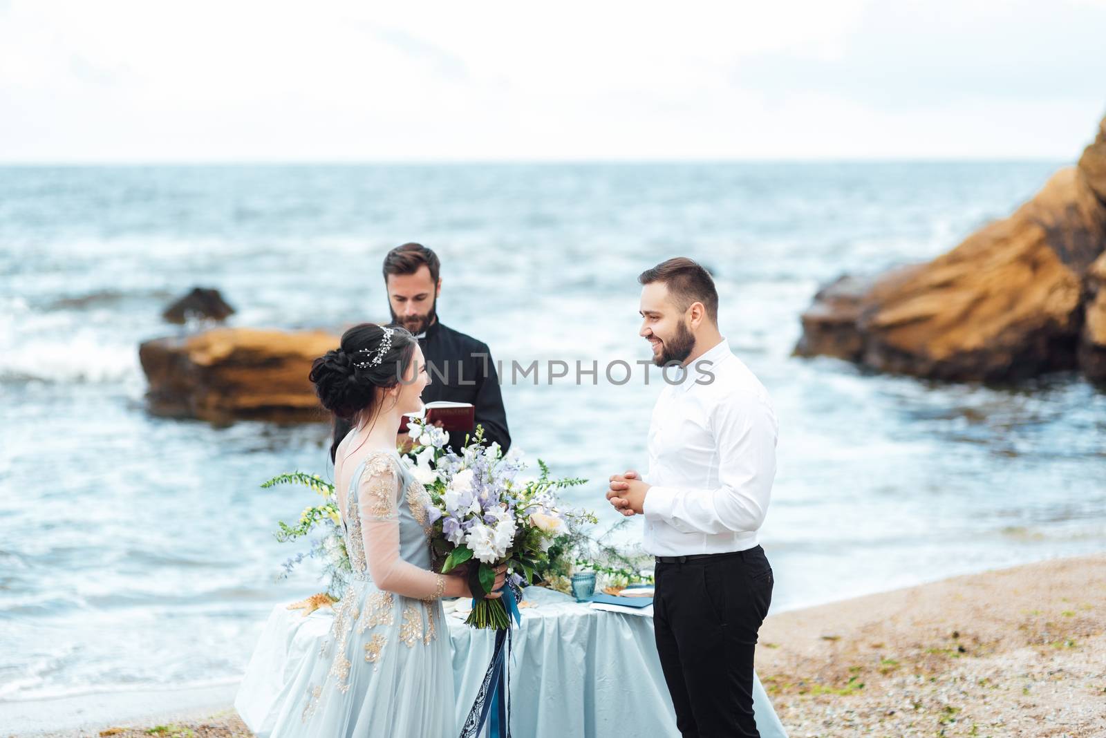 wedding couple on the ocean with a priest by Andreua