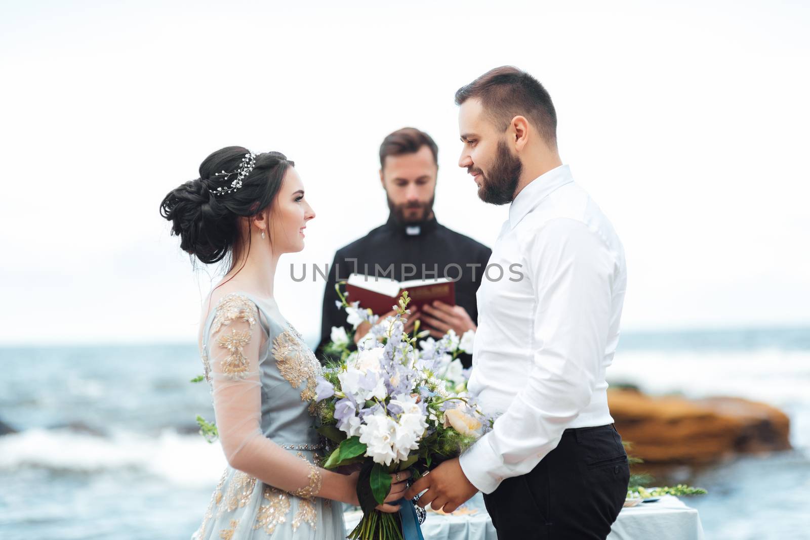 wedding couple on the ocean with a priest by Andreua