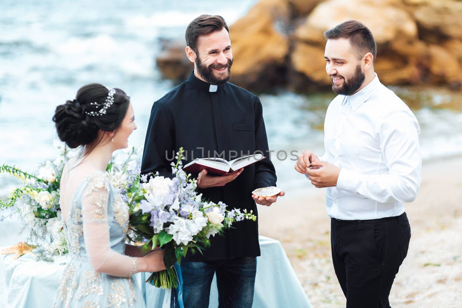 wedding couple on the ocean with a priest by Andreua