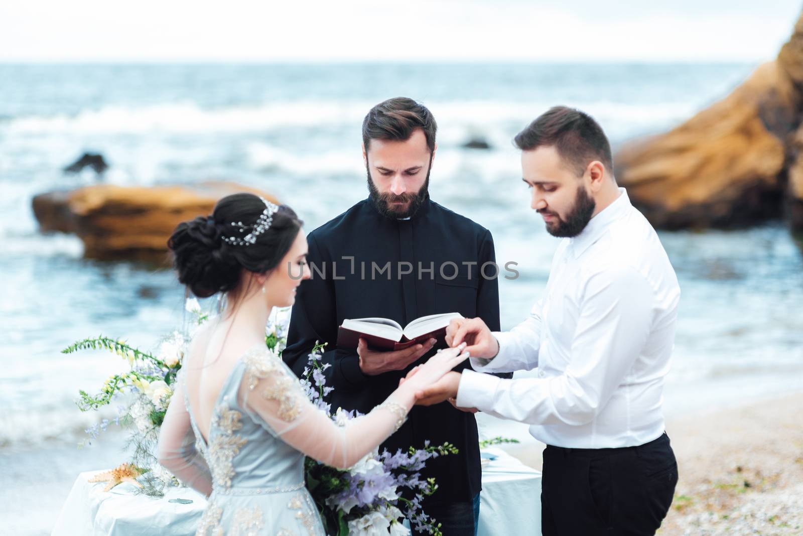 wedding couple on the ocean with a priest