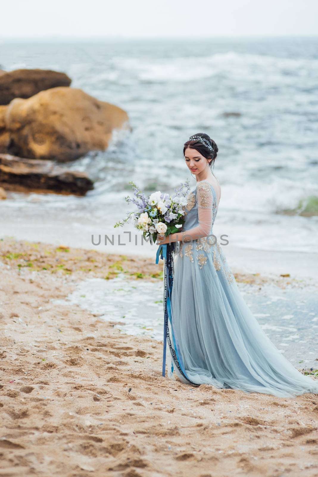 bride with a bouquet of flowers on the beach near the water